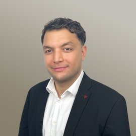 Das Bild zeigt ein Foto von dem DEPI Mitarbeiter Oguzhan Yumruk vor einem grauen Hintergrund.